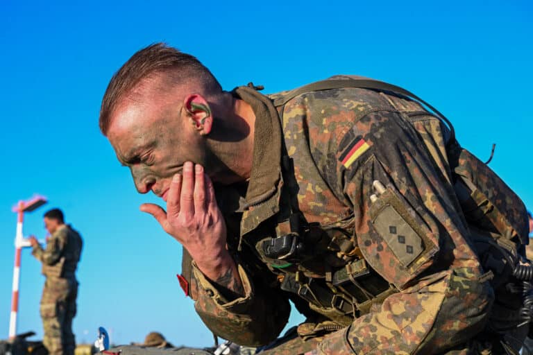A German Bundeswehr paratrooper applies face paint prior...