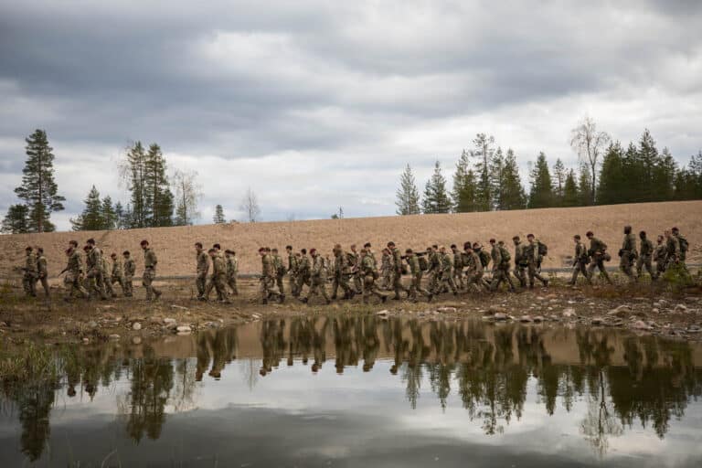 British soldiers trek across a range while moving...