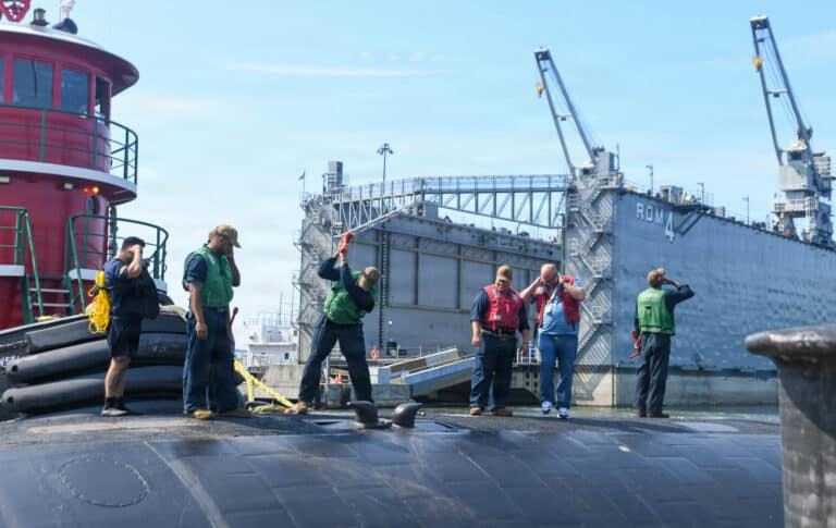 Sailors use a rubber hammer to flip cleats as Los...