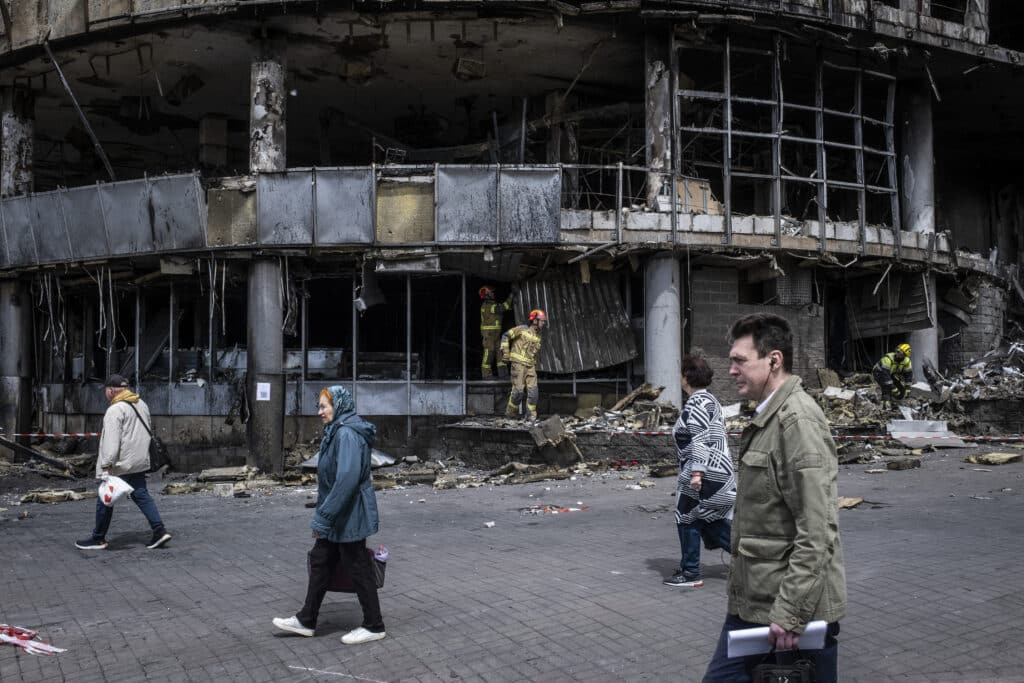 Personnes marchant devant un centre commercial détruit dans le quartier de Liukanivka à Kiev.