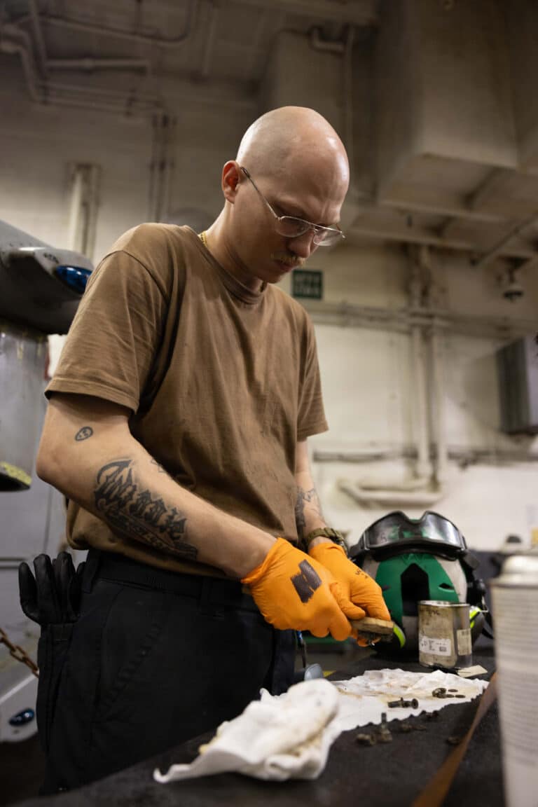 A U.S. Sailor maintains equipment for an MH-60S Sea...
