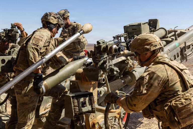 U.S. Army paratroopers load a 155mm artillery round into...
