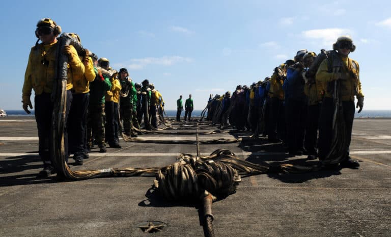 Sailors carry an aircraft crash barricade during an...