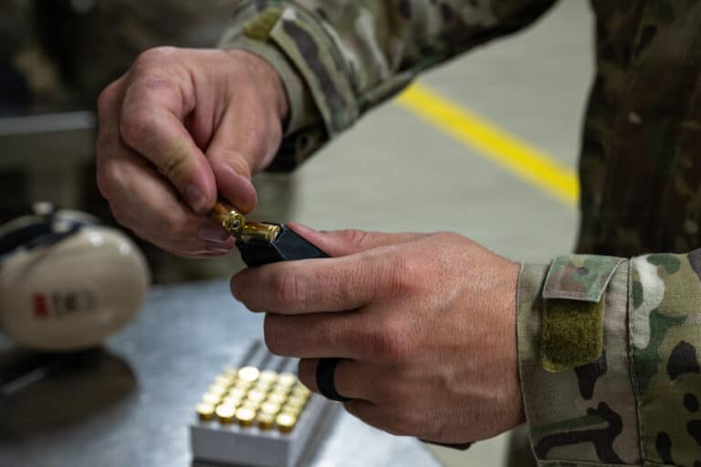 A U.S. Airman loads a magazine during a Sig Sauer M18...