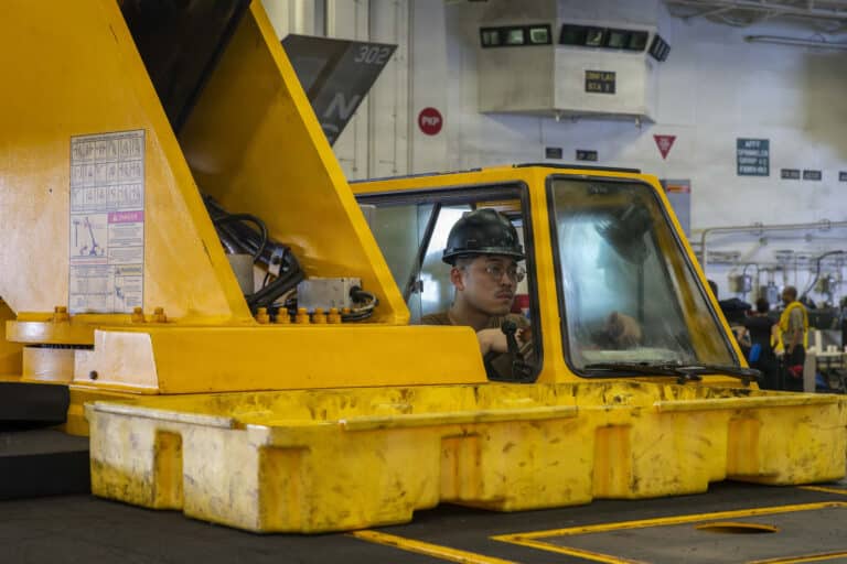 A U.S. Sailor operates a crane in the hangar bay aboard...